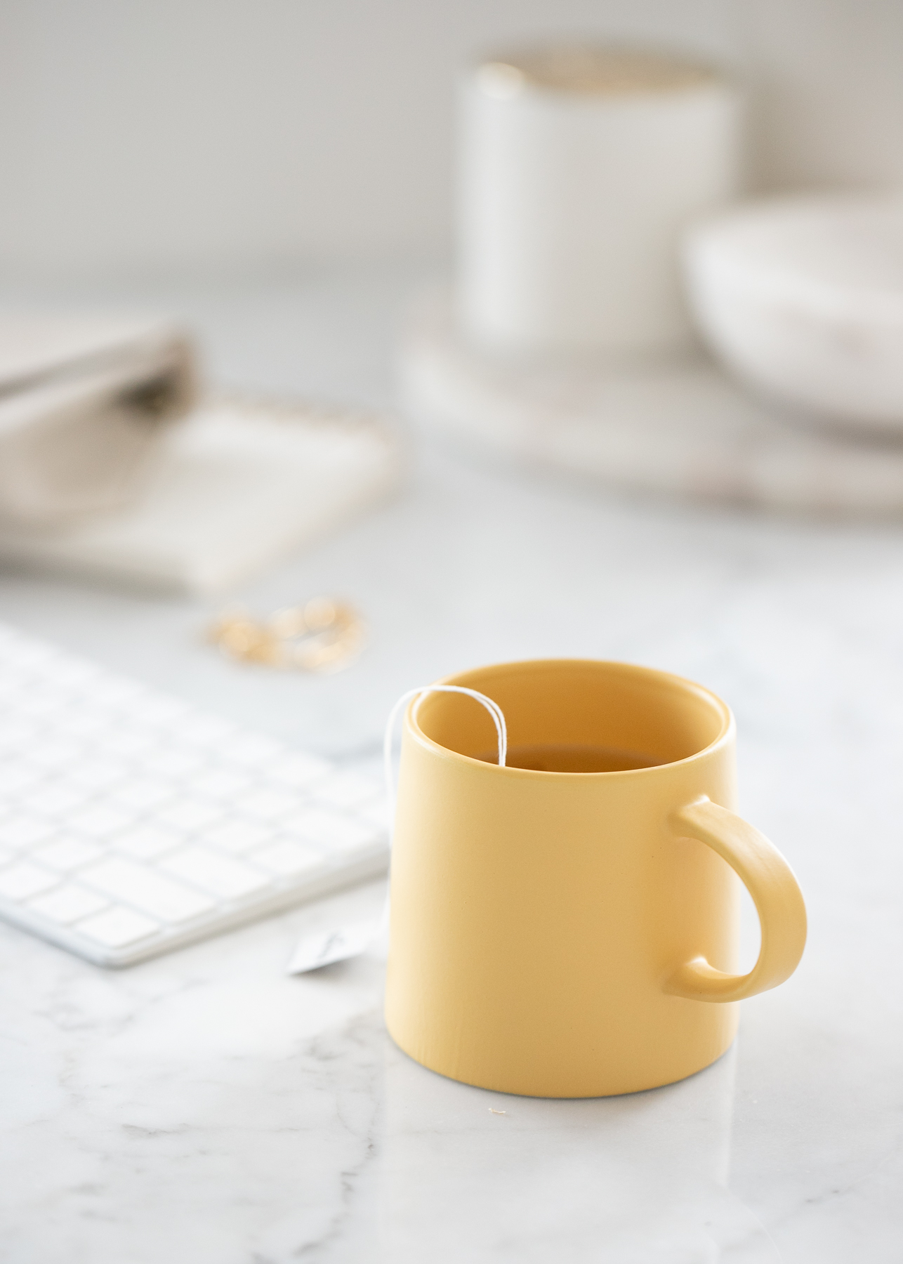 Image of a yellow coffee cup sitting on a counter with a keyboard in the background.