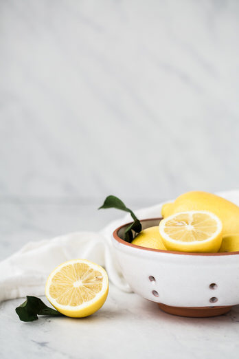 Image of a white ceramic strainer with sliced lemons.