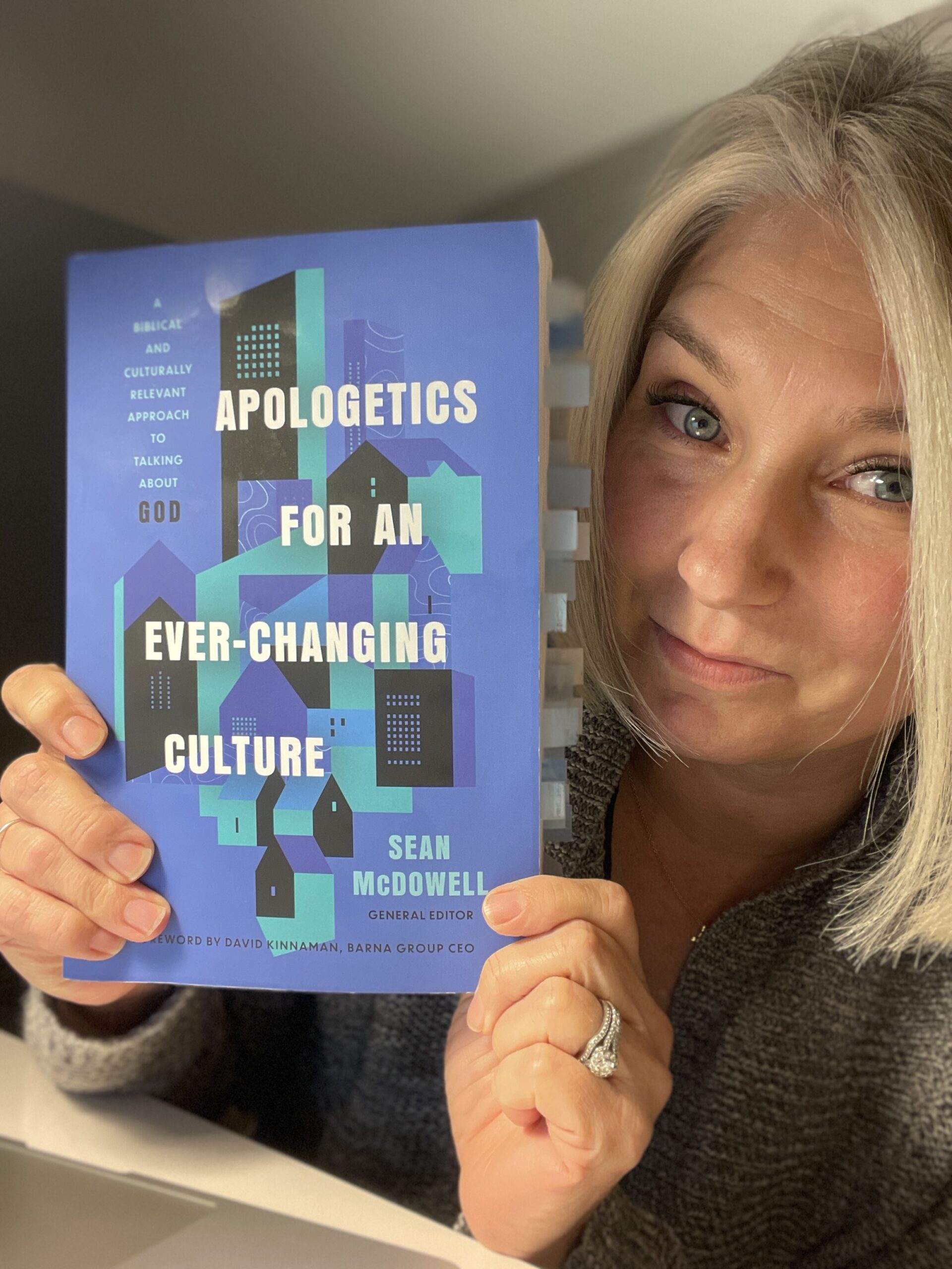 Christian Apologist Liz Cobo holding a copy of the book, Apologetics for an Ever-Changing Culture